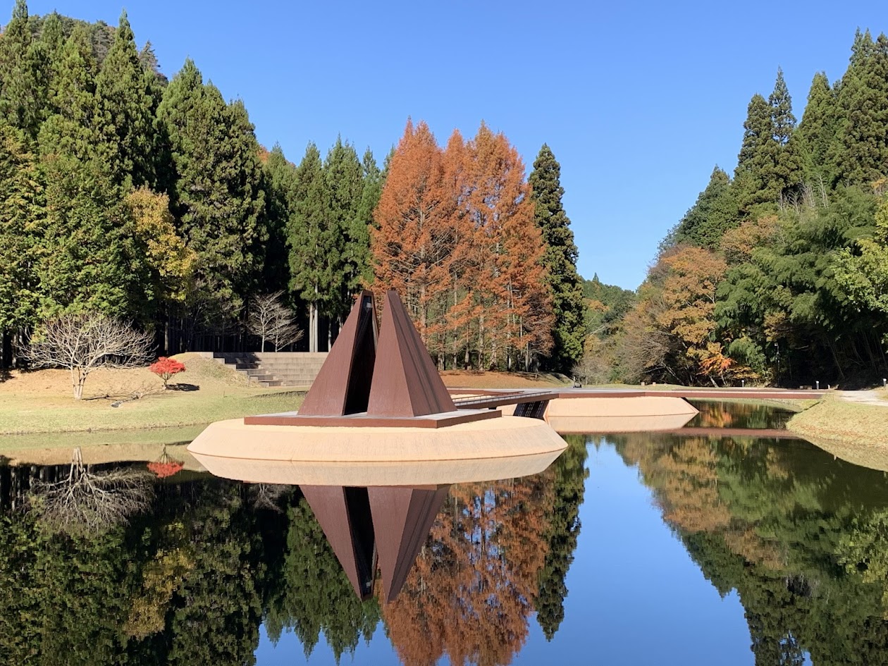 芸術の森の三角塔と池に映った景色と青空の写真 The triangular tower reflecting on the pond with a clear blue sky at the Forest of Art.