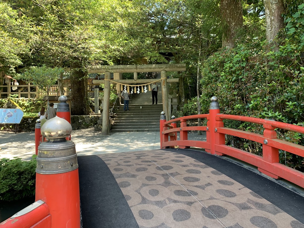 天河大辨財天社の赤色欄干の橋と石の鳥居の写真A red-railed bridge and a stone torii gate at Tenkawa Daibenzaiten Shrine.